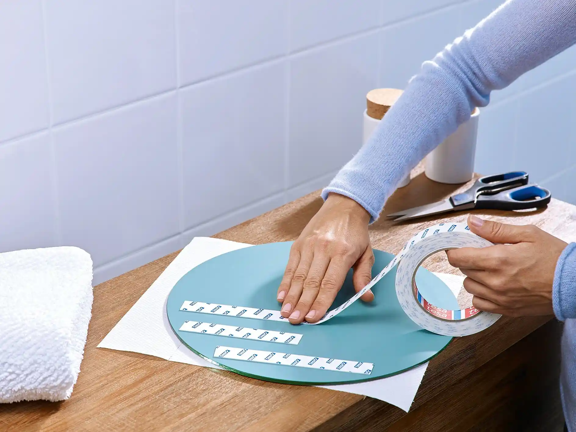 Applying double-sided mounting tape on the back of a mirror for easy, damage-free wall installation without nails.