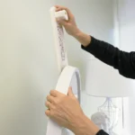 Applying strong adhesive strips to the back of a mirror for secure, damage-free wall mounting without nails.