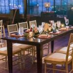 **Alt text:** Elegant dining table setup with gold chairs, candles, and glassware in a stylish restaurant dining space.