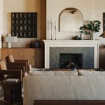 A warm, stylish living room with an arched mirror above the fireplace, enhancing depth and elegance.