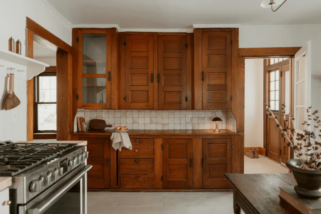 Traditional kitchen with rich brown solid wood cabinets, white tile backsplash, stainless steel gas range, and natural light from wooden framed windows