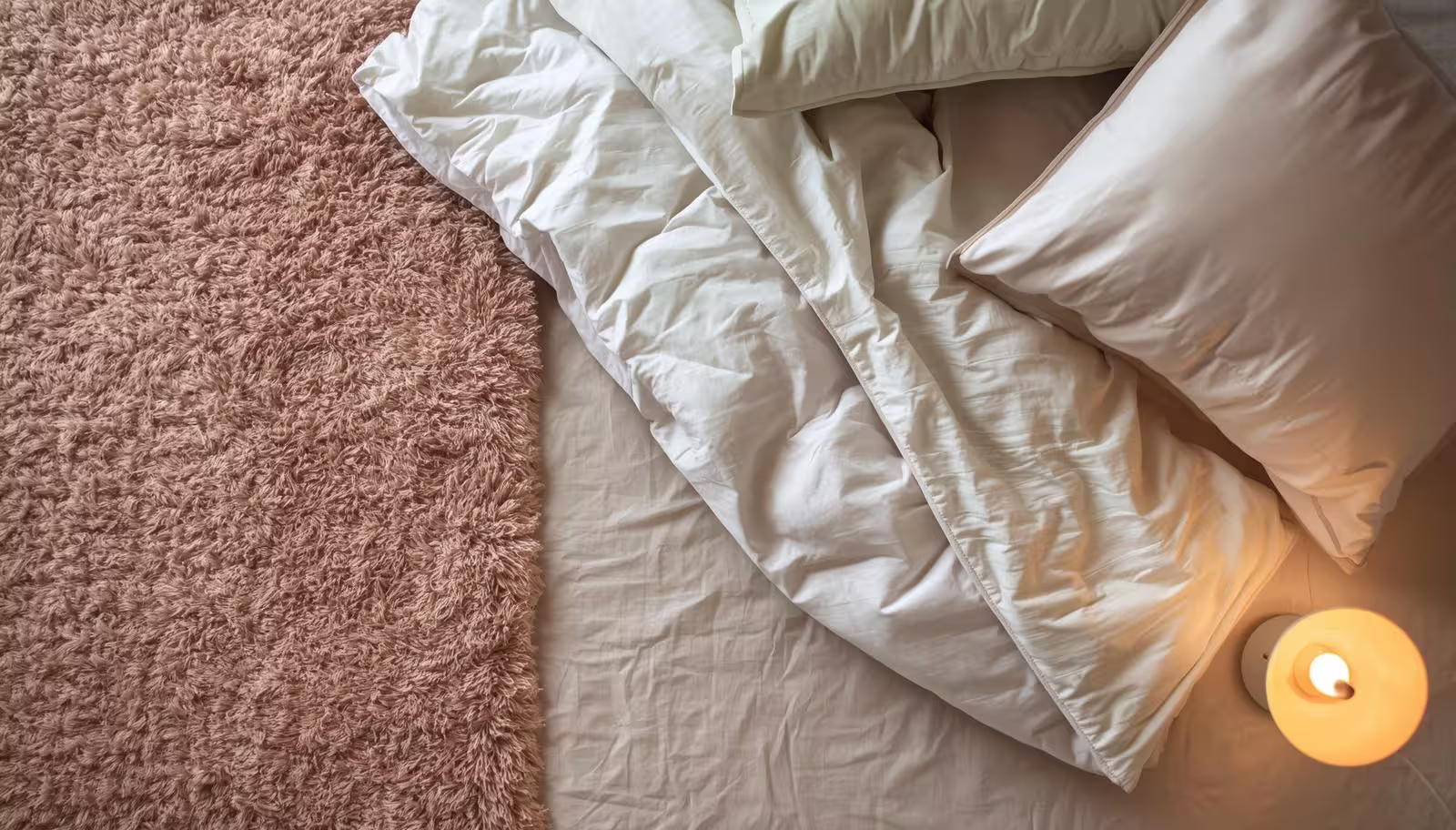 Flat lay of neutral bedding, rug corner, and warm lamp labeled as a “smart spend” essentials setup.